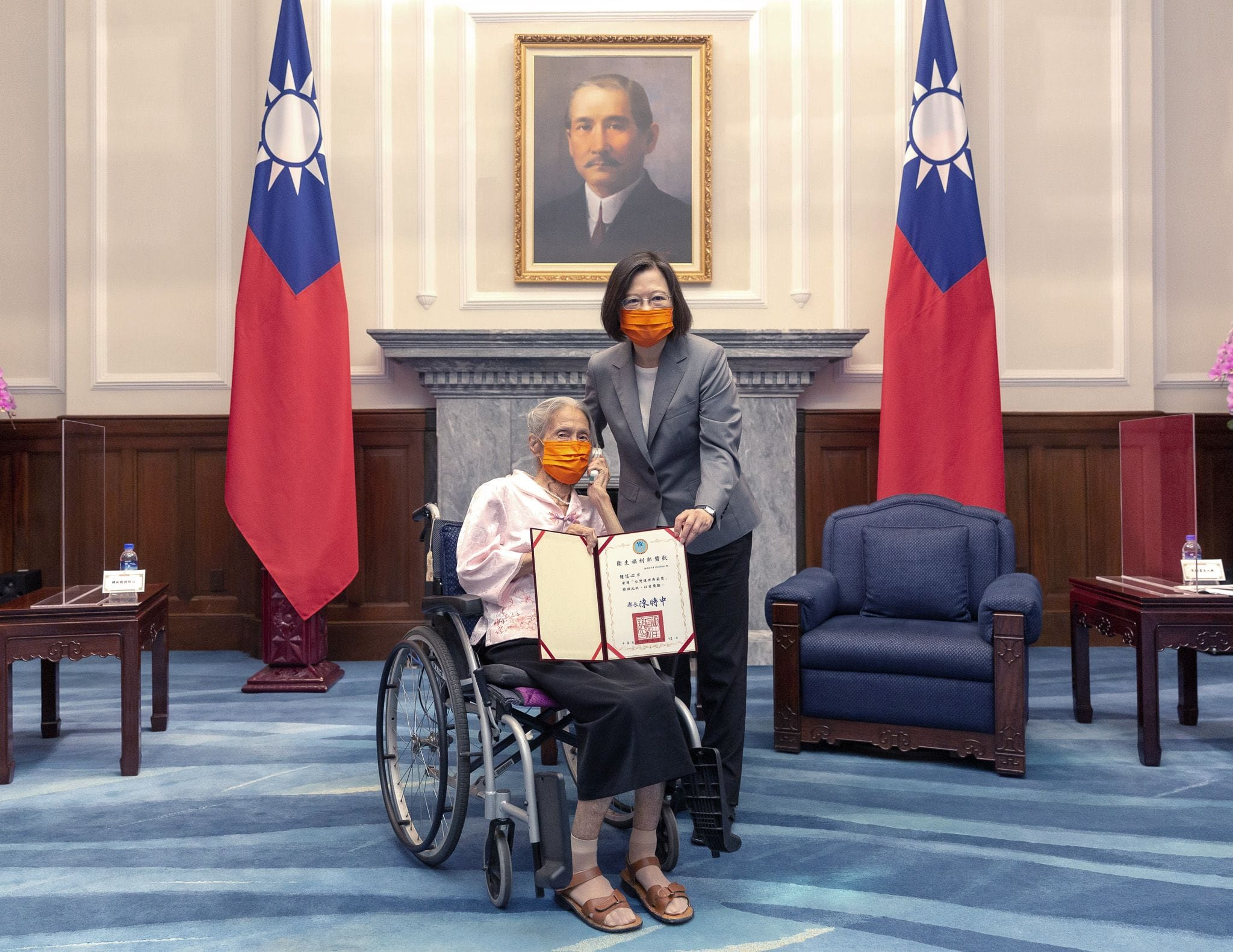 一位女士乘坐輪椅於總統府受總統頒獎