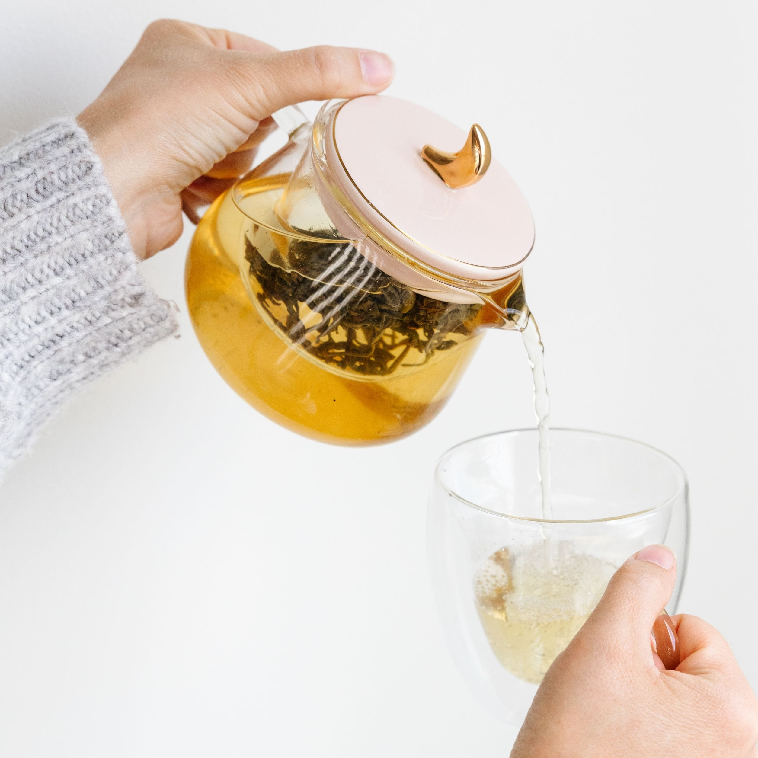  A woman pouring tea from a teapot into a mug
