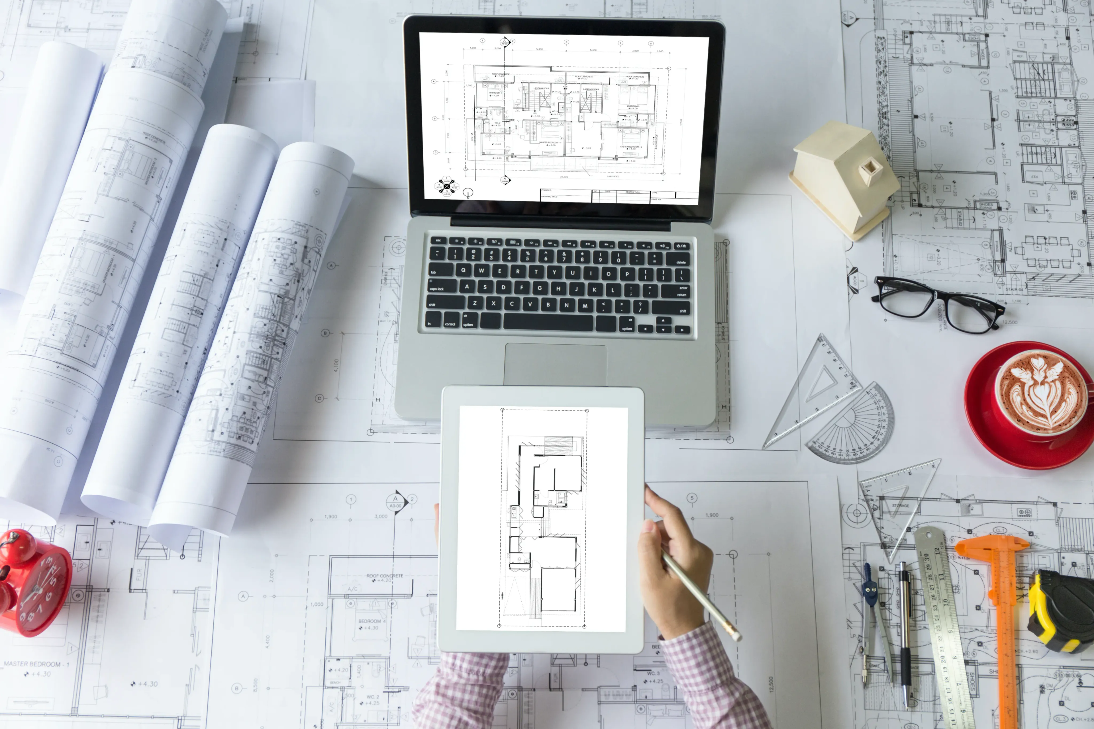 Architect working on blueprints using laptop and tablet