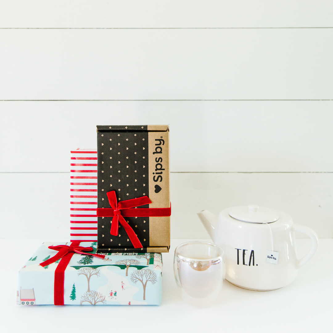 Cozy tea gifts wrapped with a cup of tea and Sips by Box with a red bow on top