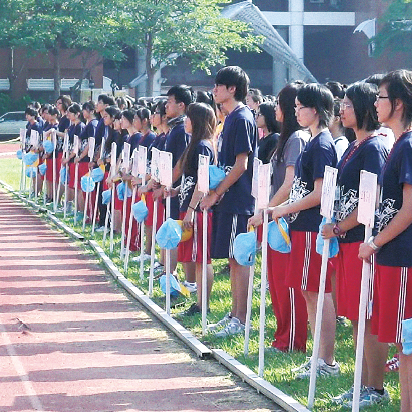 穿著運動服的學生拿著手舉台並列站好