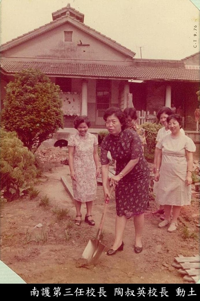 五位女士微笑合影，其中一位拿著鏟子於建物前面挖土