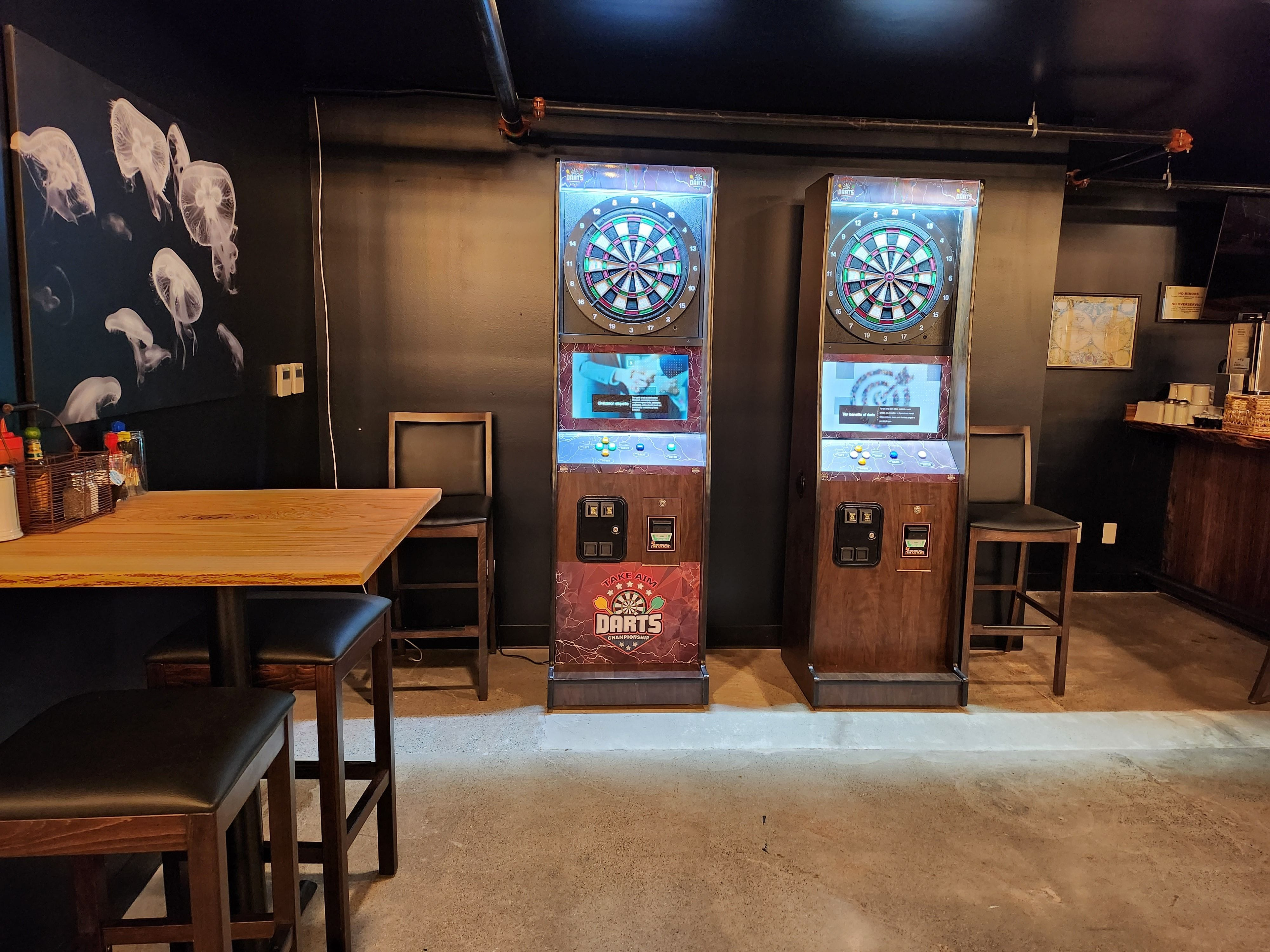 Two dart machines next to a painting of a school of jellyfish