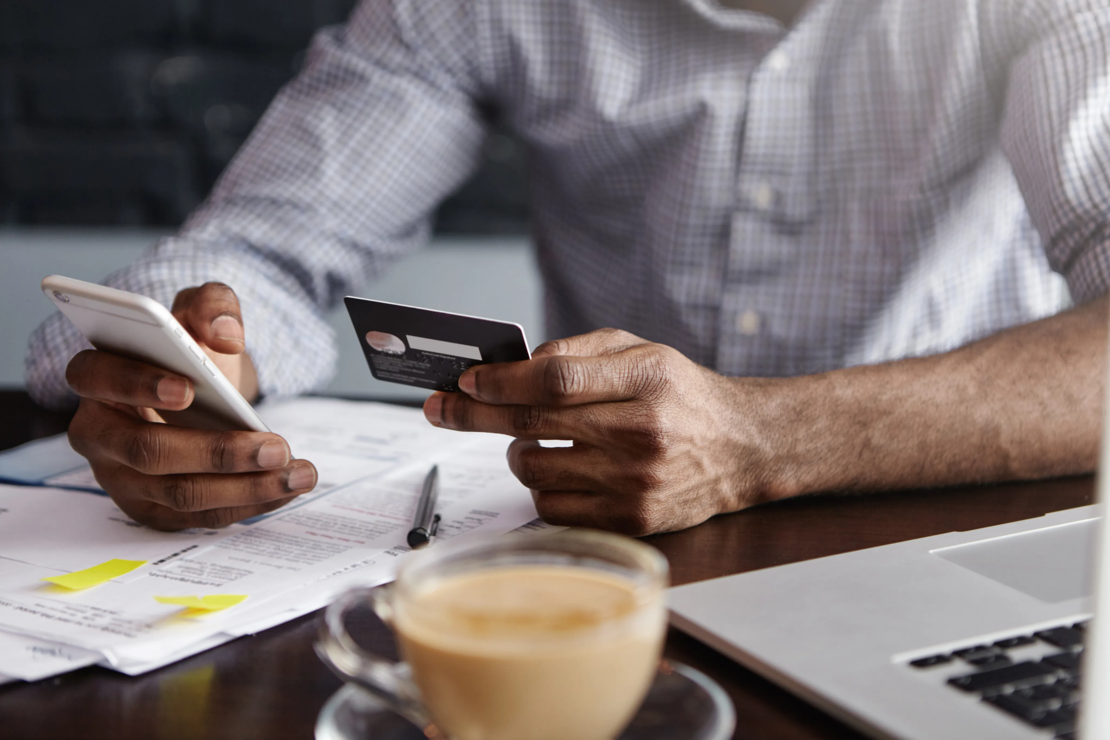 Man using a credit card while on his phone