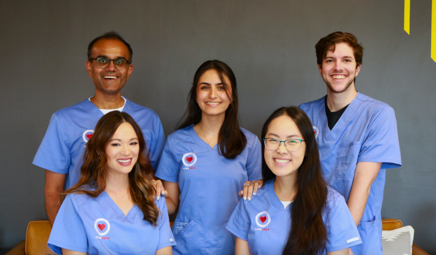 careyaya team of 5 smiles at camera in blue scrubs