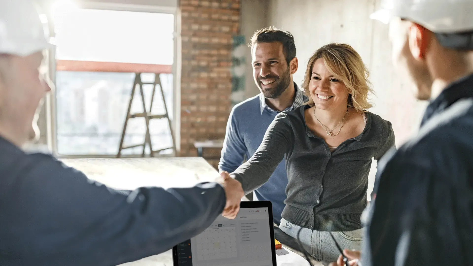 Homeowners shaking hands with construction professionals