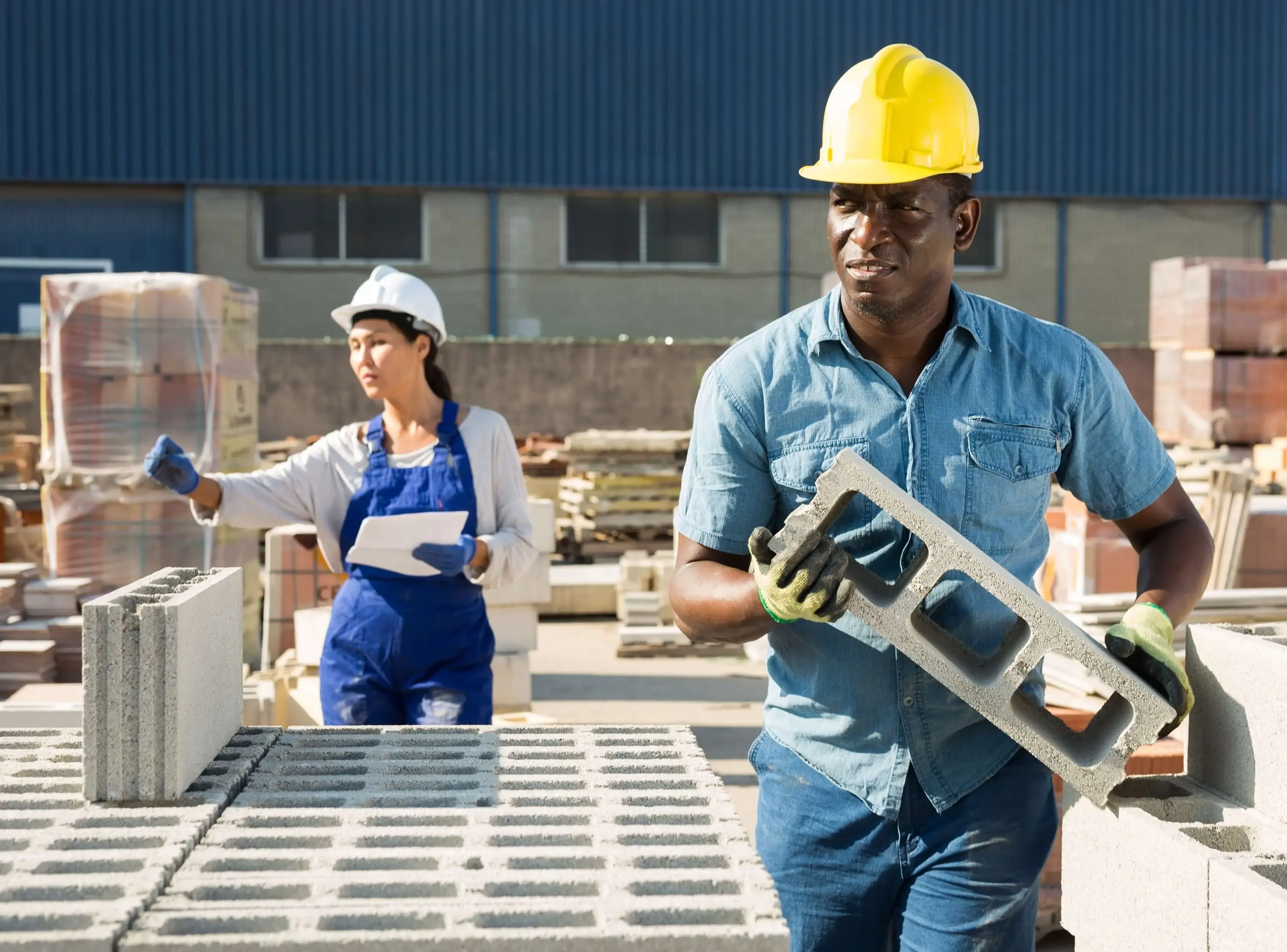 LBM supplier carrying building material with worker in background.
