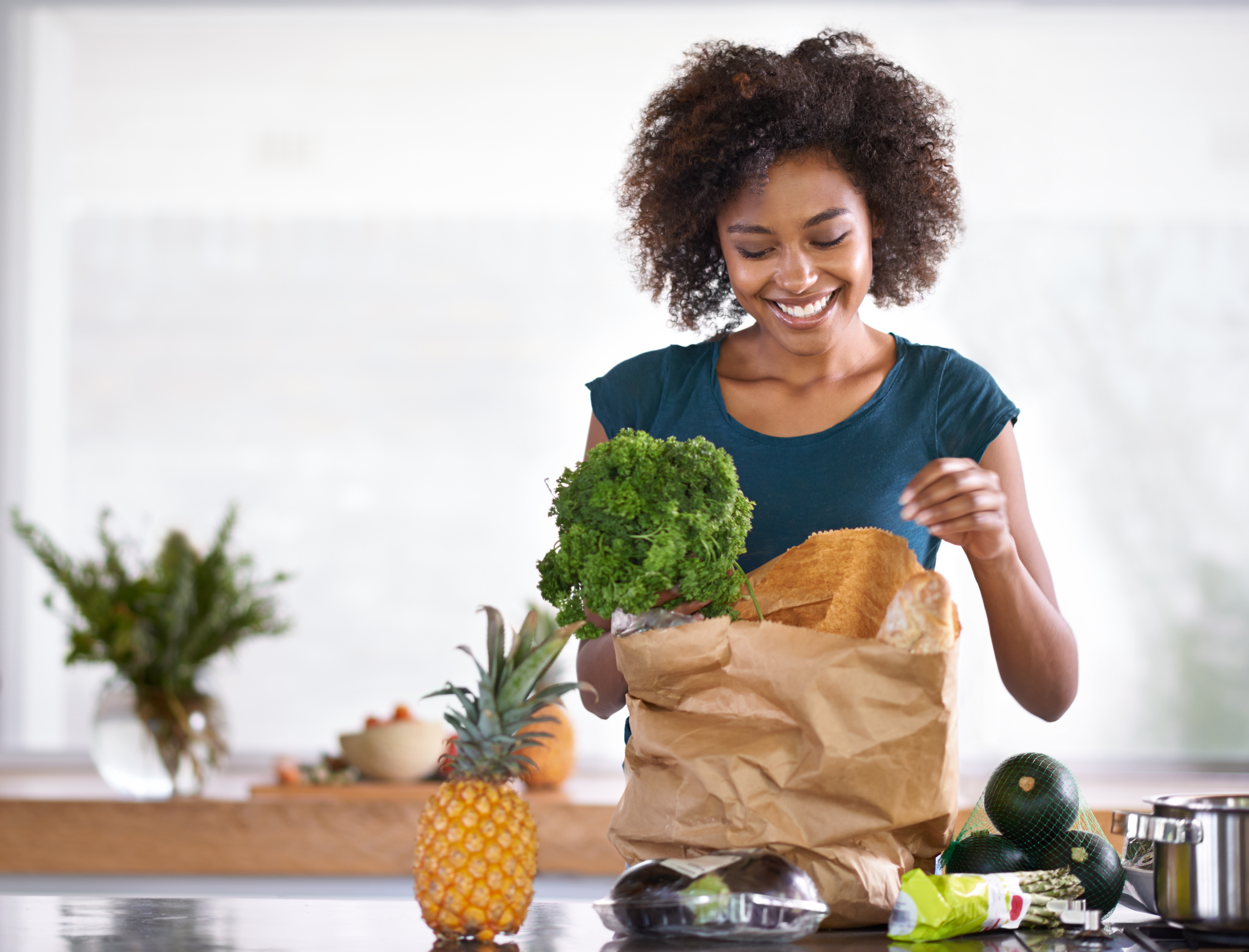 Photo of a smiling woman preparing a meal for her family while on a video chat with her registered dietitian