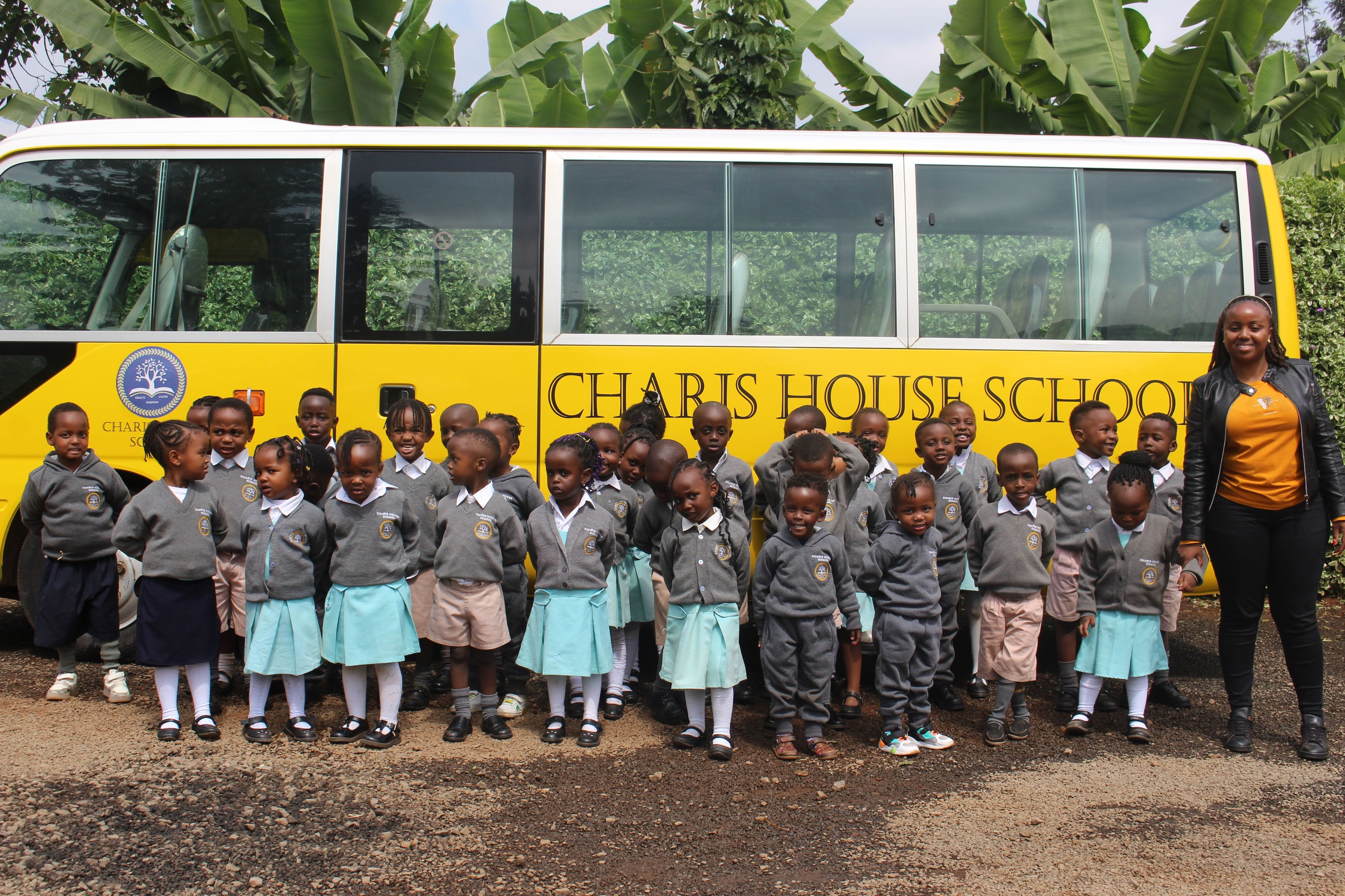 children and school admin in front of the school bus