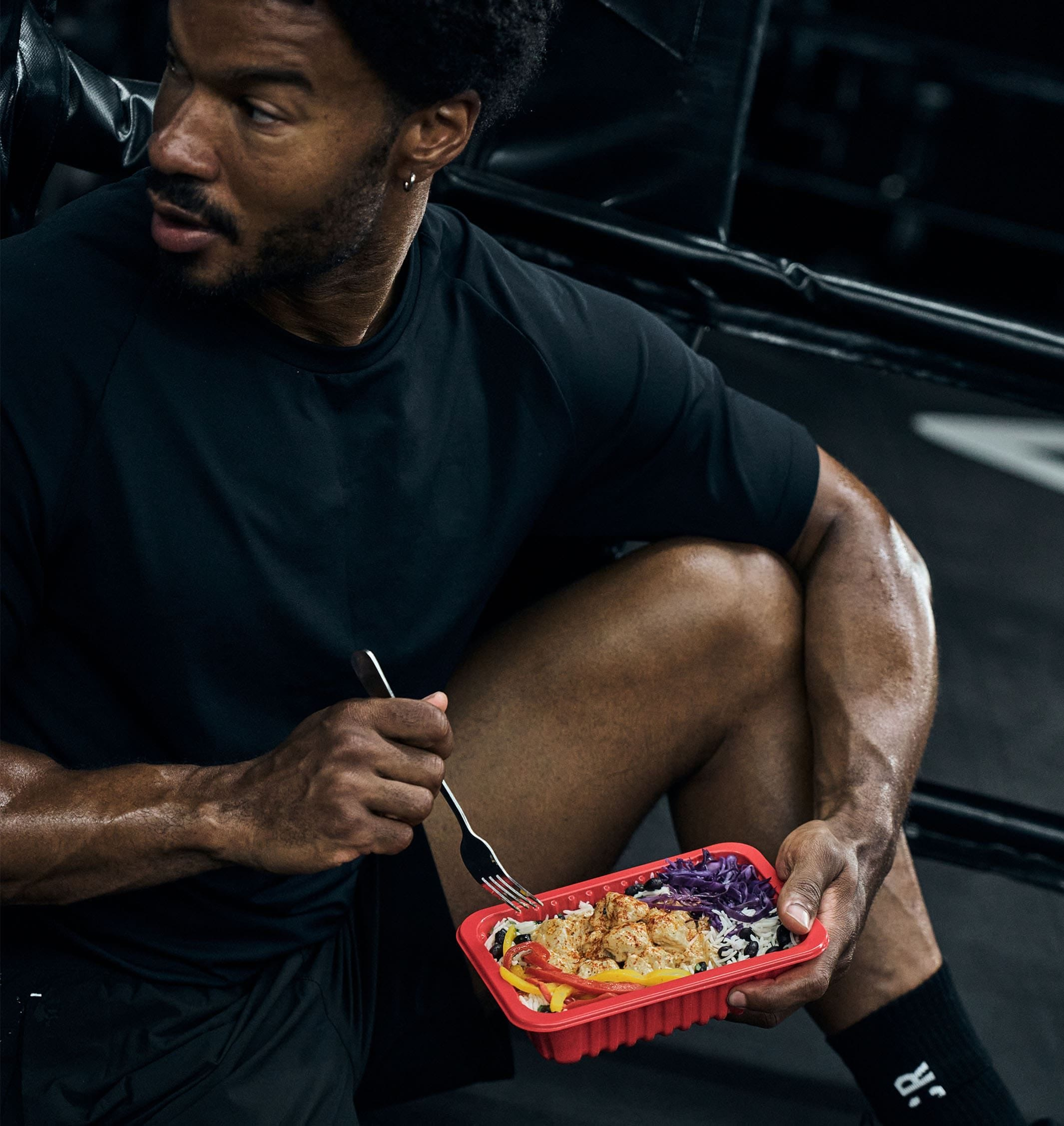 Man enjoying a healthy meal with chicken, broccoli, and sweet potatoes, alongside a My Muscle Chef meal package.
