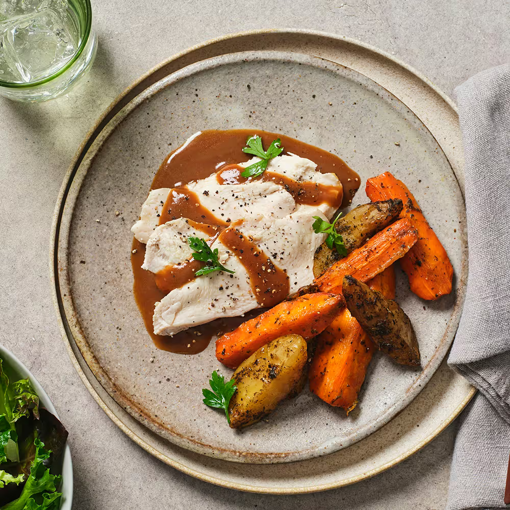 Man enjoying a healthy meal with chicken, broccoli, and sweet potatoes, alongside a My Muscle Chef meal package.