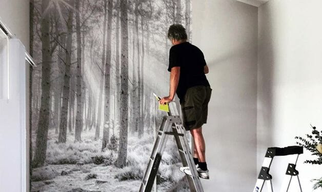 man installing wallpaper mural