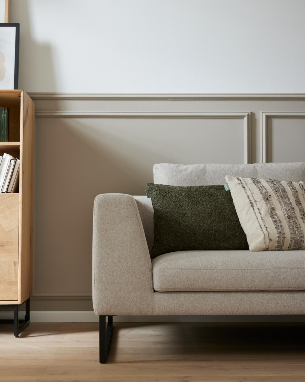 Helles, modernes Wohnzimmer mit cremefarbener Couch, Zierkissen in Naturtönen, runder Couchtisch mit Dekoobjekten und Wandkunst – skandinavischer Wohnstil mit minimalistischer Einrichtung und Wohlfühlatmosphäre.