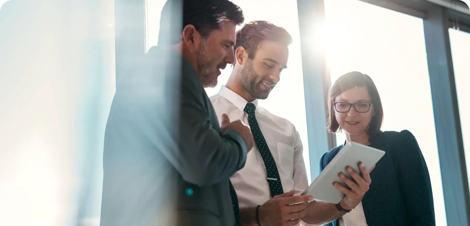 Businesspeople gathered around a tablet, smiling