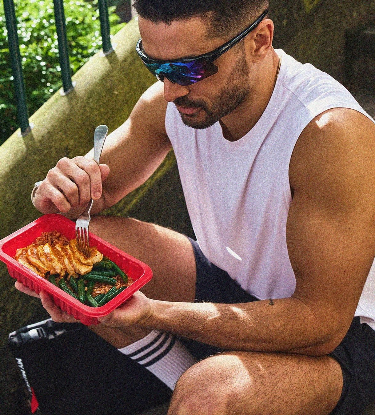 Man enjoying a healthy meal with chicken, broccoli, and sweet potatoes, alongside a My Muscle Chef meal package.