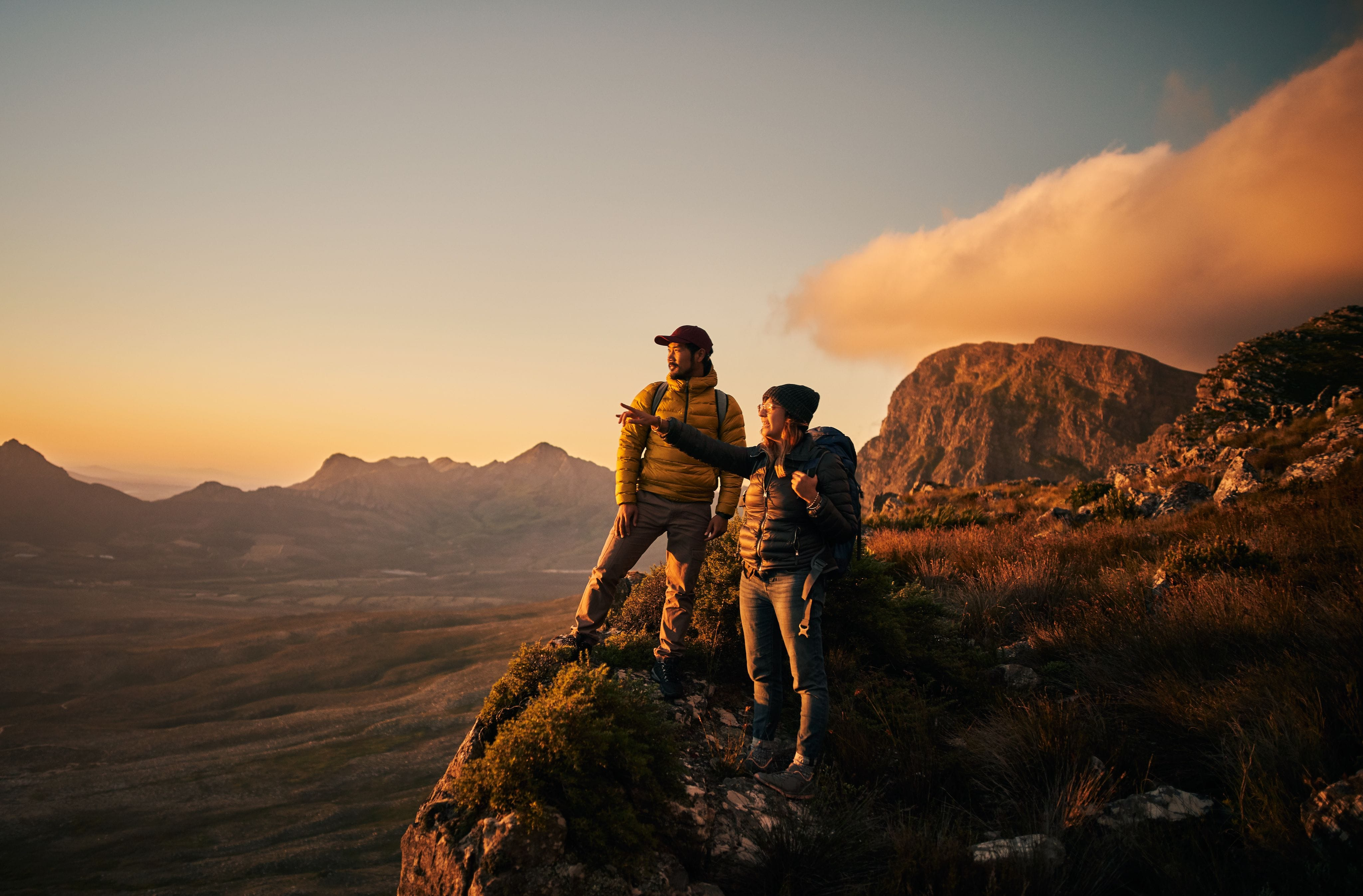 Two hikers on a mountain summit enjoy the view, symbolizing reaching a new level.