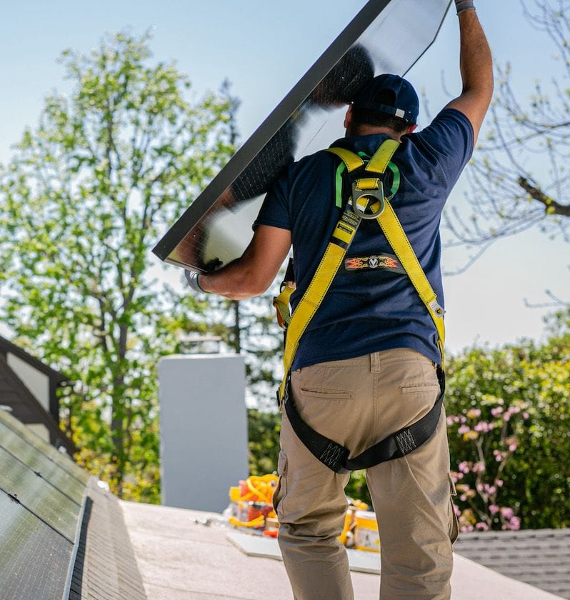 Palmetto solar installer carries panel on roof