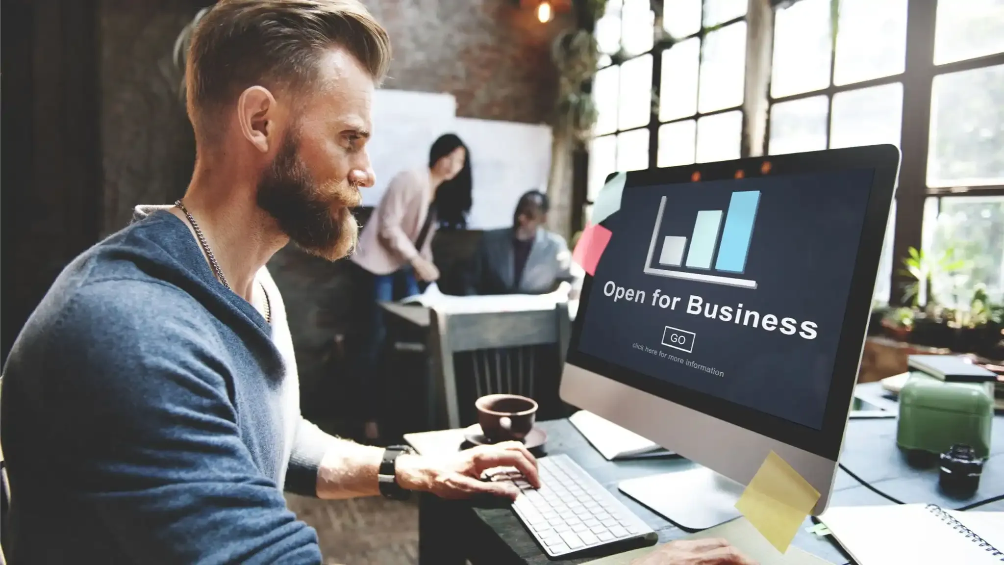 Man working at computer, screen saying "Open for Business"