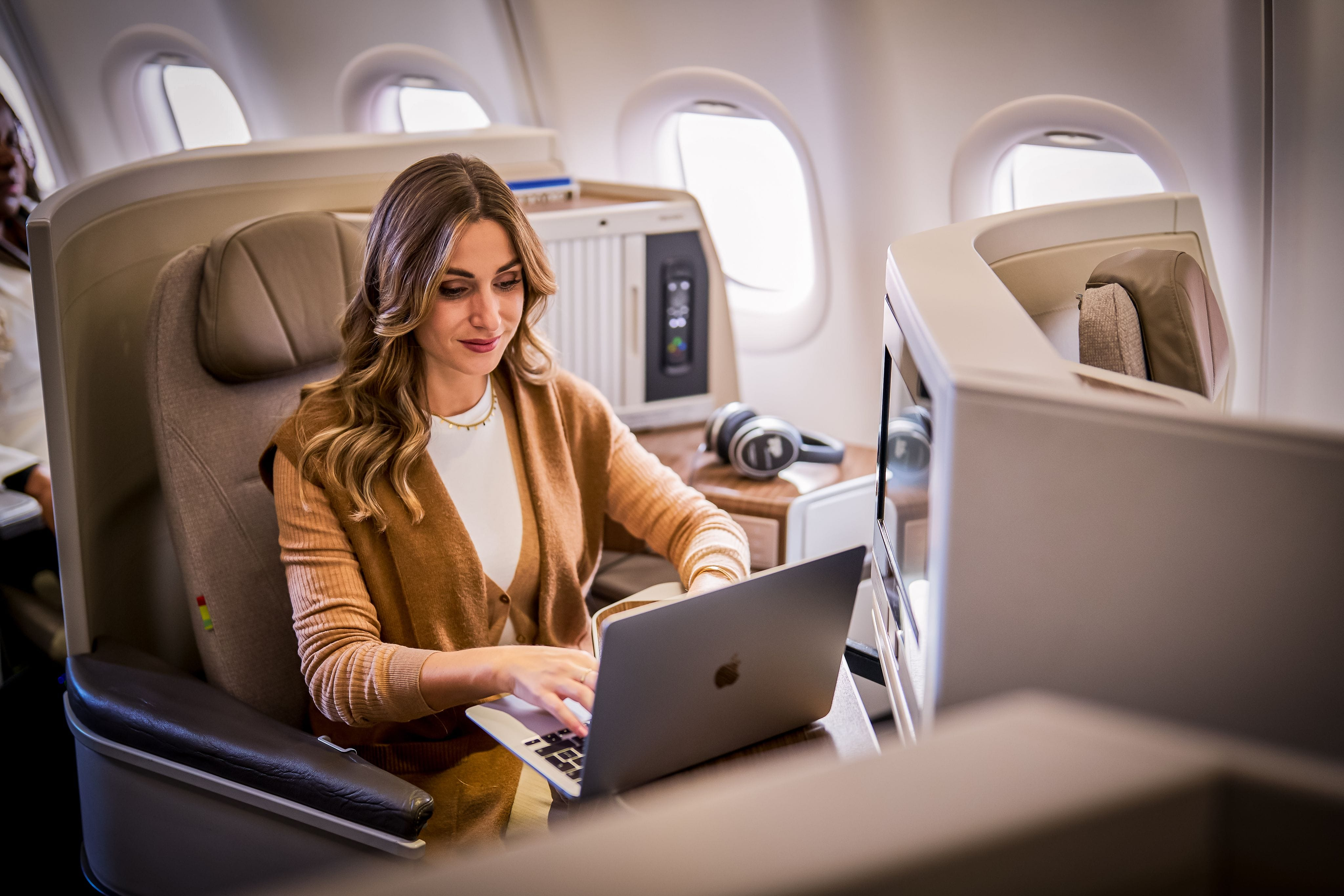Woman sitting in an airplane with her laptop open