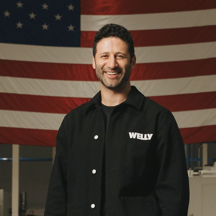 Welly team member in front of an American flag in the factory