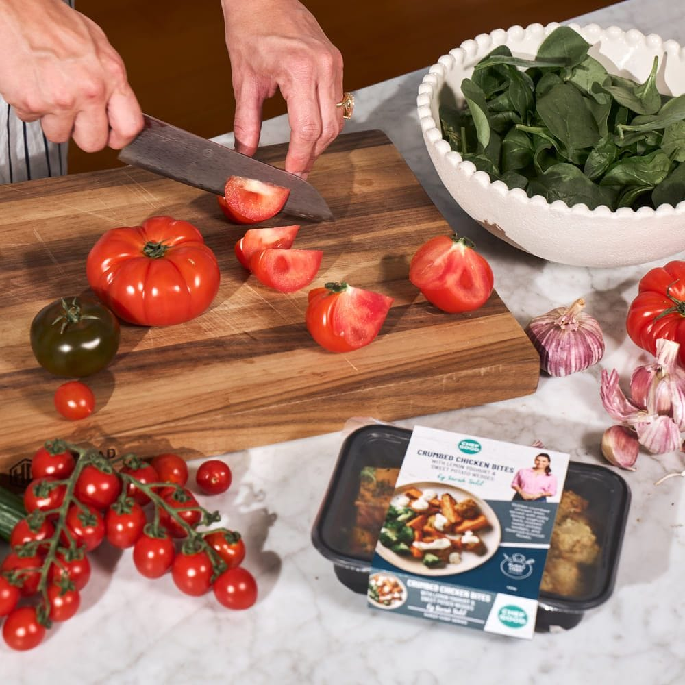 Man enjoying a healthy meal with chicken, broccoli, and sweet potatoes, alongside a My Muscle Chef meal package.