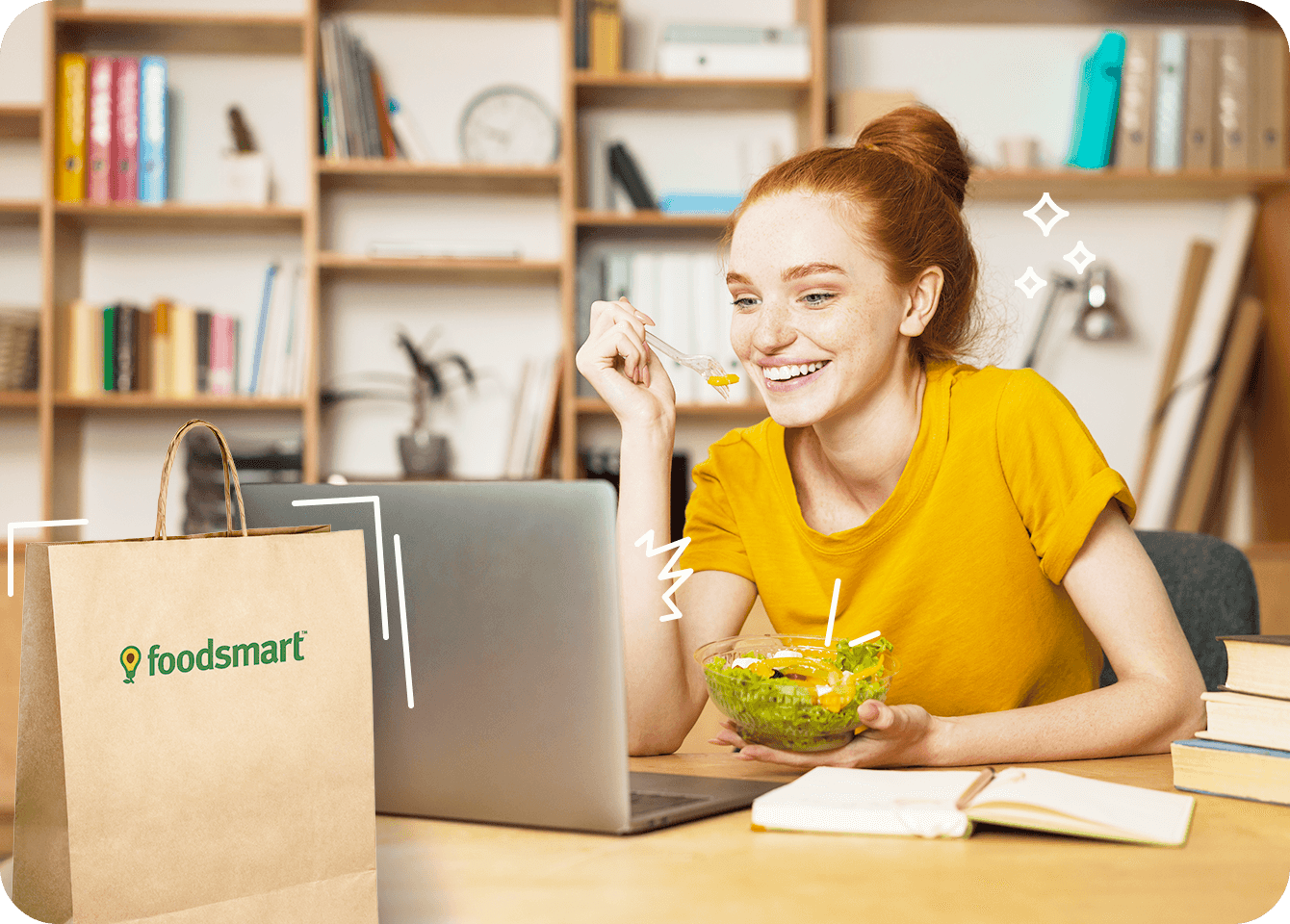 Photo of a young woman eating a salad while using her computer