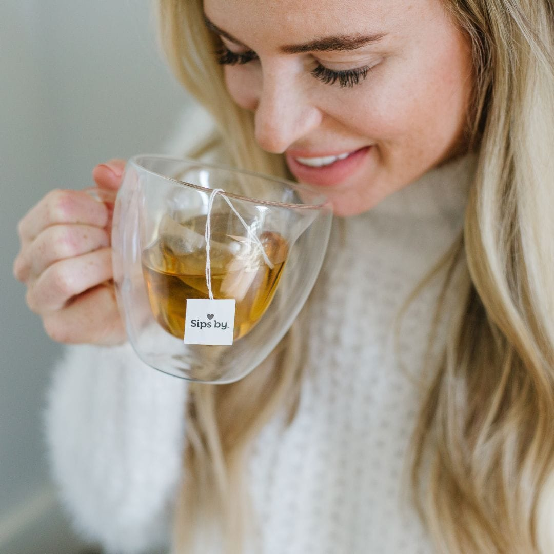 Blond woman drinking tea from glass mug