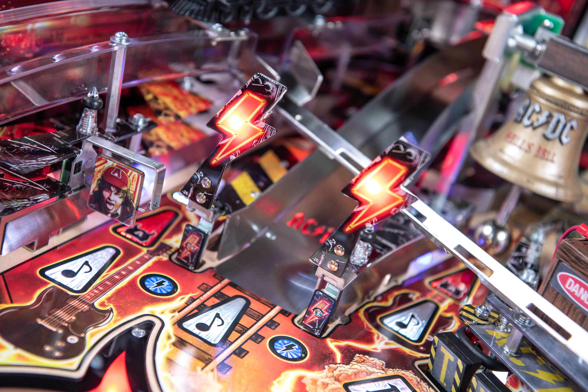 Two illumniated lighting bolts with a custom cut metal ramp on the AC/DC Remastered pinball machine by Stern Pinball.